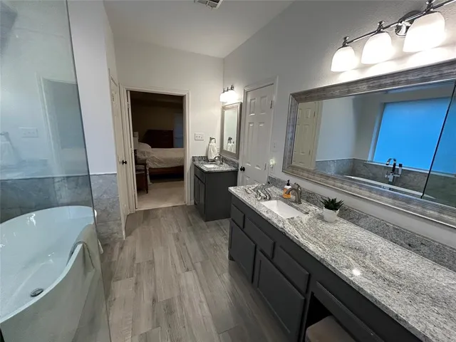 a bathroom with a granite countertop tub sink and mirror
