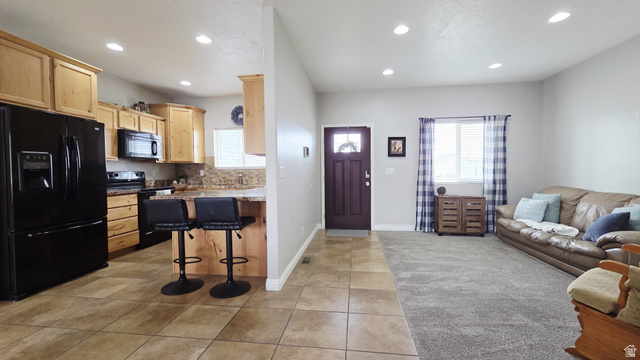 1437 925 South Vernal, UT 84078 - Photo 2 of 47 Open-concept living space featuring a kitchen with wood cabinetry and black appliances, a breakfast bar, and tile flooring