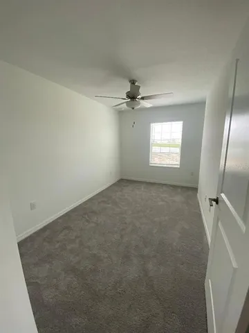 an empty room with windows and fan