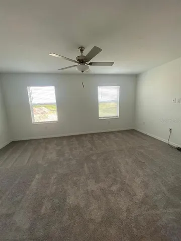 an empty room with windows and ceiling fan view