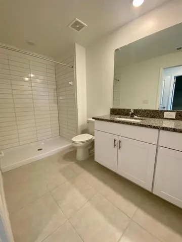 a bathroom with a granite countertop sink a toilet a mirror a bathtub and shower