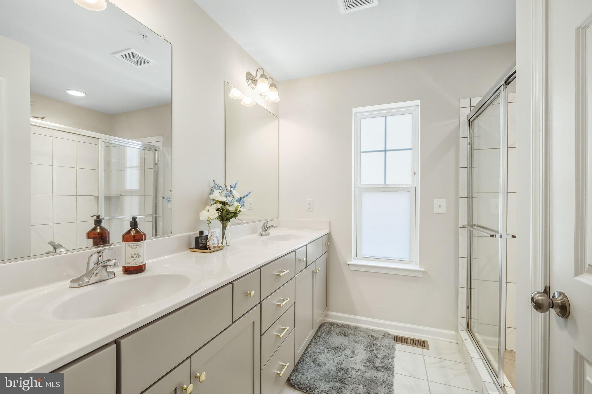 15635 Trolley Lane Silver Spring, MD 20906 - Photo 22 of 41 a bathroom with a double vanity sink a mirror and a shower