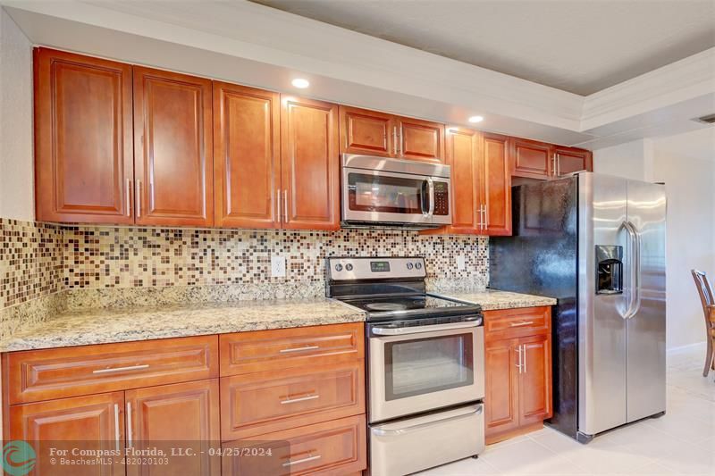 a kitchen with granite countertop wooden cabinets and stainless steel appliances