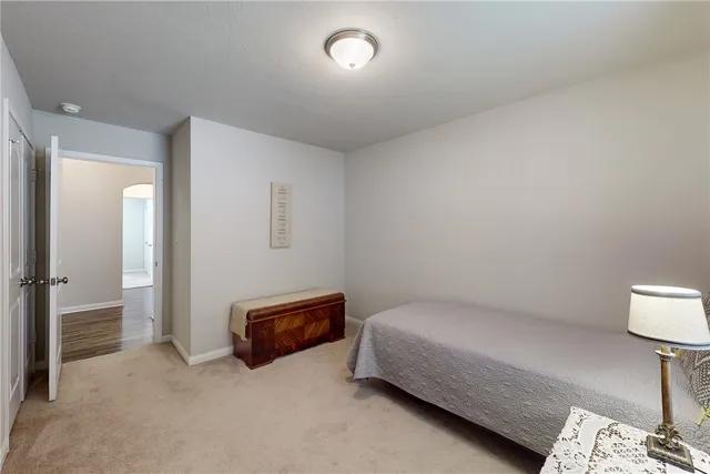 a spacious bedroom with a bed and a lamp