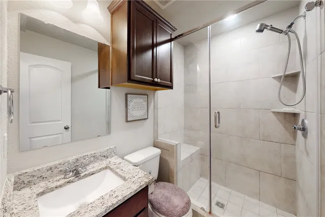 a bathroom with a granite countertop sink a toilet and shower