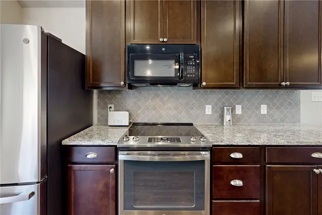 a kitchen with granite countertop stainless steel appliances wooden cabinets and a counter top