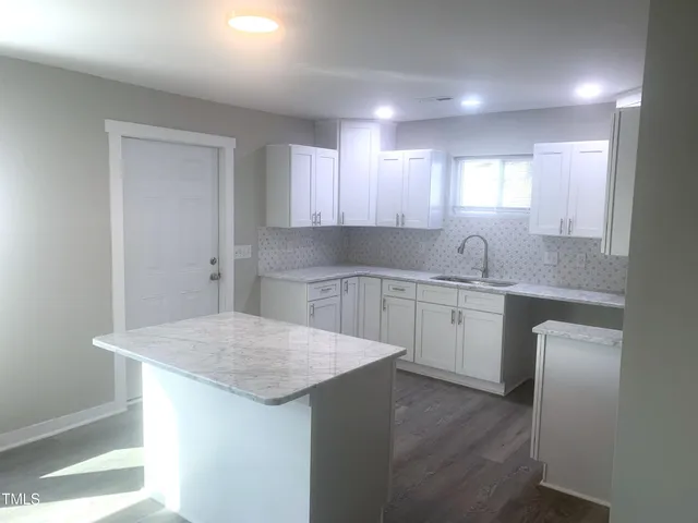 a kitchen with a sink a stove a refrigerator and white cabinets