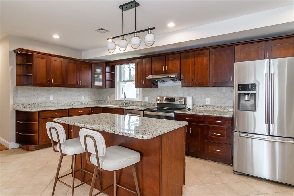 3 Leighton Street Natick, MA 01760 - Photo 4 of 31 a kitchen with stainless steel appliances granite countertop a refrigerator a sink dishwasher a stove a kitchen island with a dining table and chairs