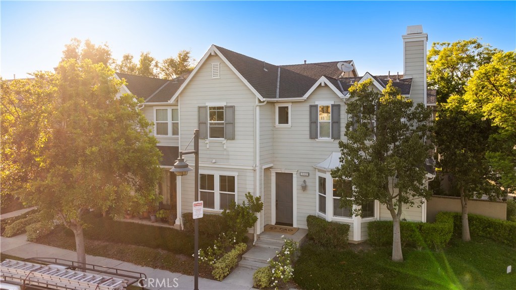 a view of a white house next to a yard with big trees