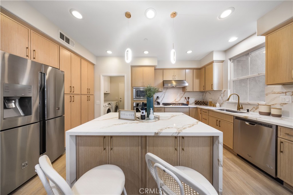 15525 Bonsai Way Tustin, CA 92782 - Photo 15 of 40 a kitchen with stainless steel appliances granite countertop a sink a stove a refrigerator cabinets and chairs