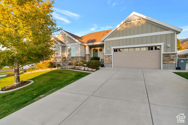 898 Burke Lane Elk Ridge, UT 84651 - Photo 1 of 1 Craftsman-style home with board and batten siding, stone siding, a front yard, a garage, and concrete driveway