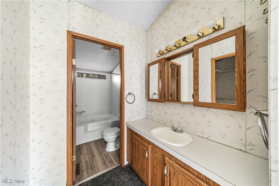 3792 Selnik Road Kent, OH 44240 - Photo 11 of 39 Full bath featuring a textured ceiling, toilet, vanity, and wallpapered walls