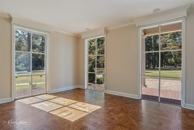 a view of an empty room with a window and wooden floor