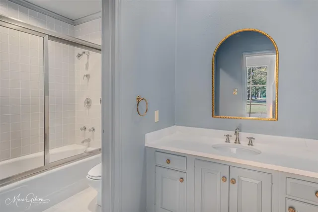 a bathroom with a granite countertop sink a toilet and shower