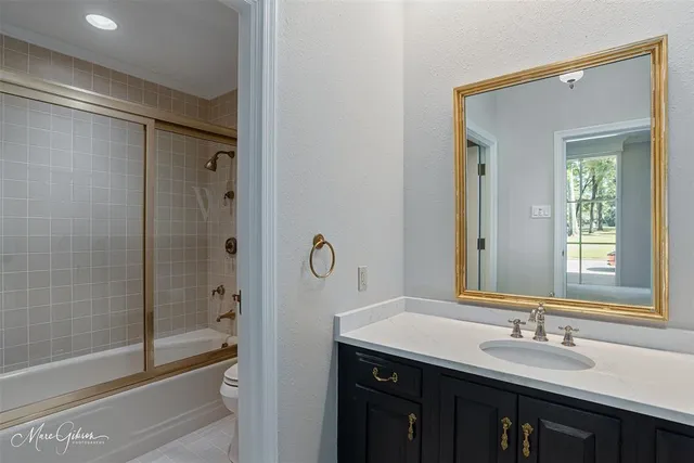 a bathroom with a granite countertop sink mirror and a bathtub