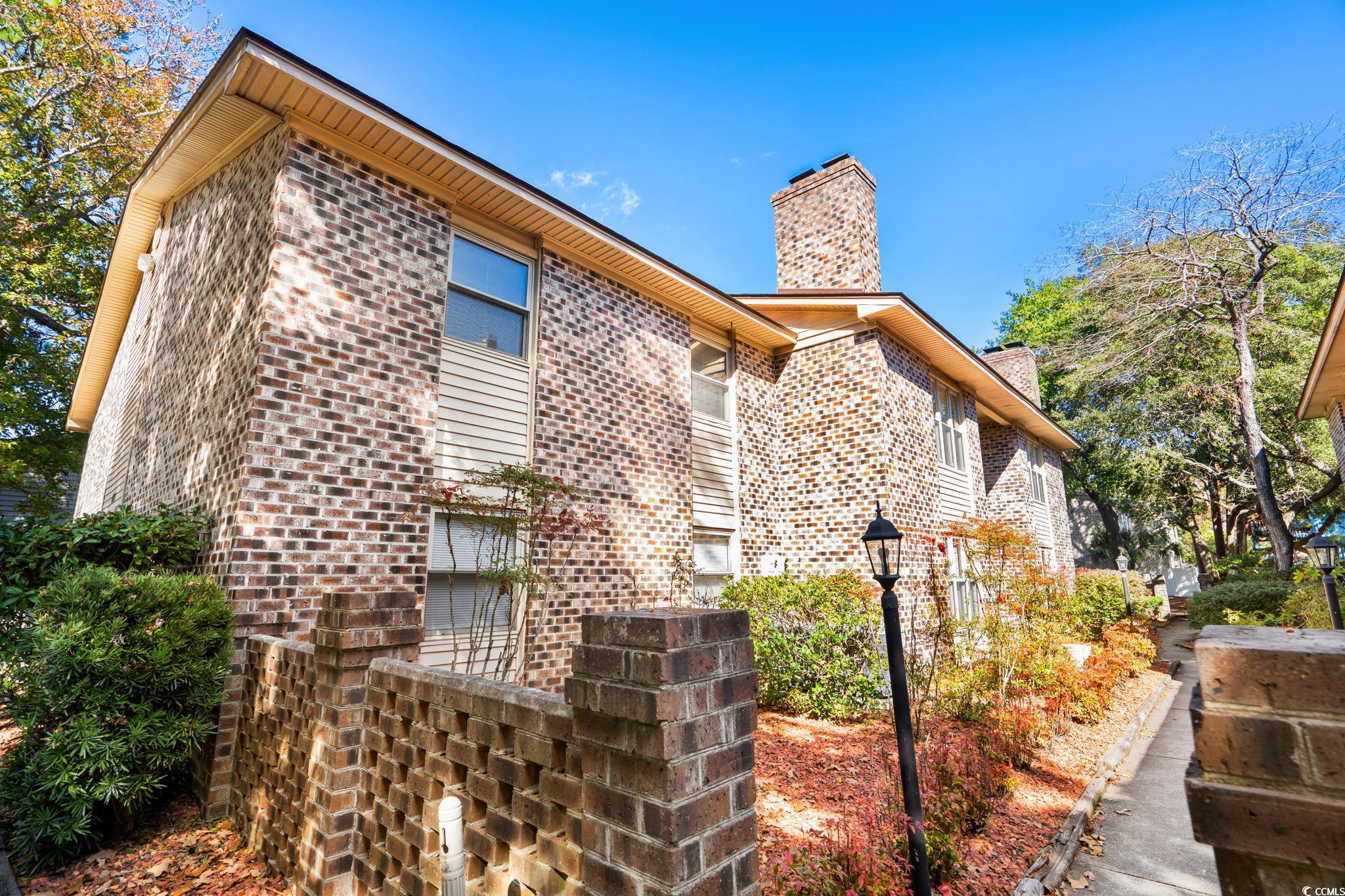 View of property exterior featuring a chimney and brick siding