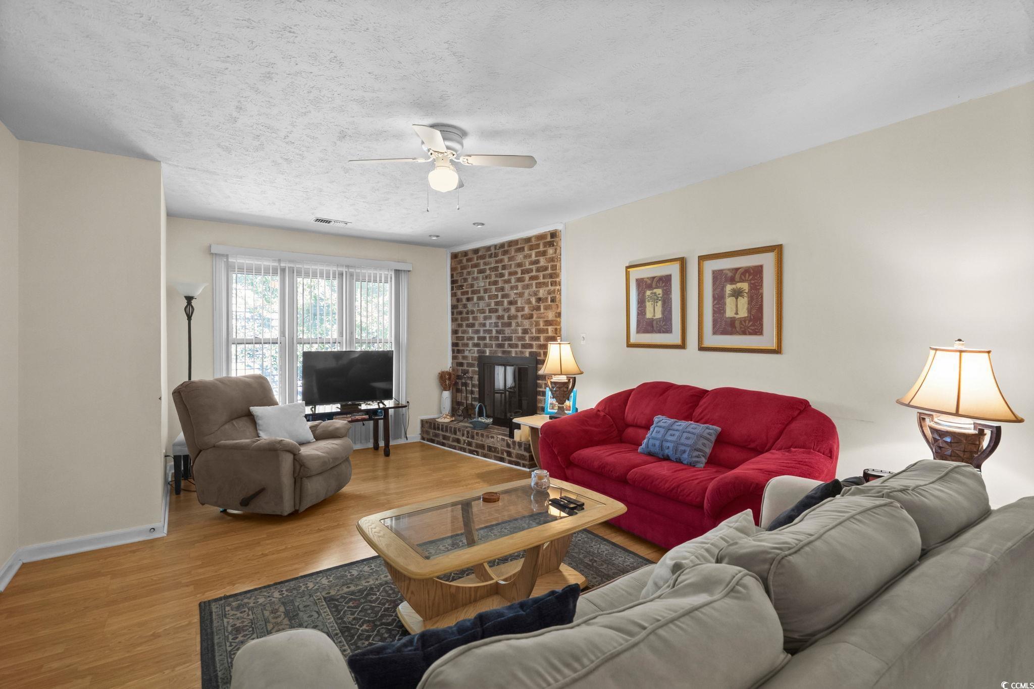 406 75th Avenue North, Unit Q Myrtle Beach, SC 29572 - Photo 5 of 23 Living area featuring wood finished floors, ceiling fan, a textured ceiling, and a fireplace