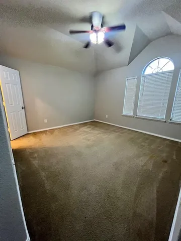 an empty room with a ceiling fan and a window