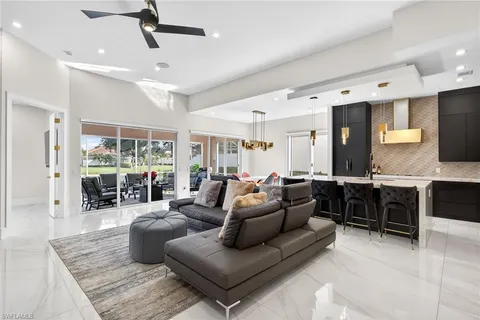 a living room with furniture kitchen view and a large window