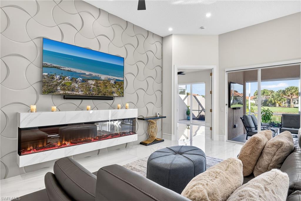 3956 Isla Ciudad Court Naples, FL 34109 - Photo 7 of 39 Living room featuring ceiling fan, a premium fireplace, an accent wall, recessed lighting, and light marble finish floors