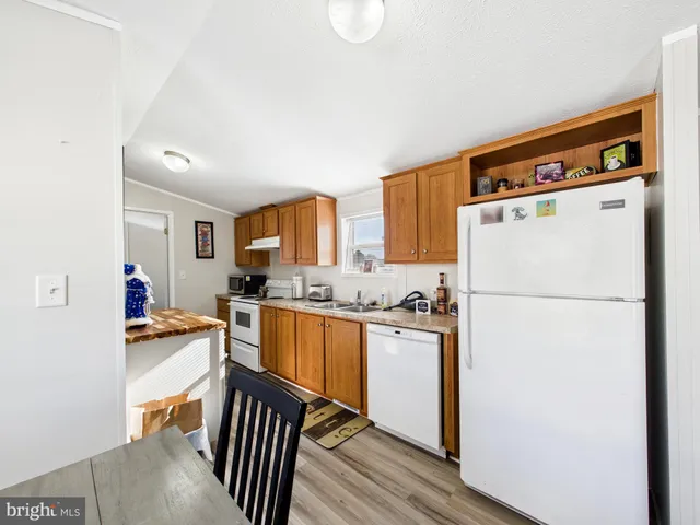 a kitchen with stainless steel appliances a refrigerator a stove a sink dishwasher and white cabinets with wooden floor