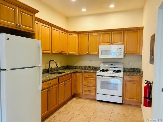 a kitchen with stainless steel appliances granite countertop a refrigerator sink stove and white cabinets