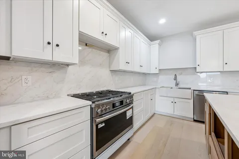 a kitchen with granite countertop white cabinets and stainless steel appliances