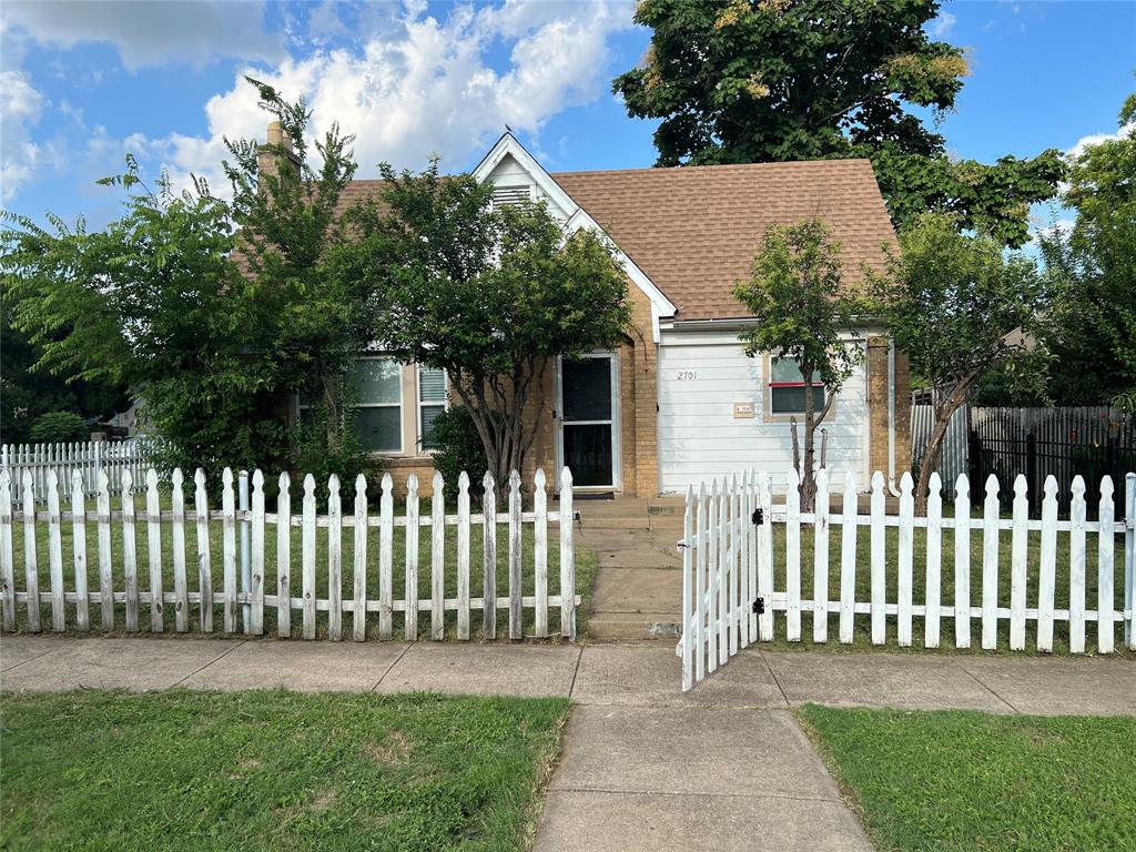 a view of a house with a small yard and a large tree