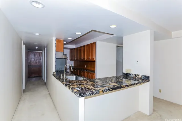 a kitchen with kitchen island granite countertop a sink and a refrigerator