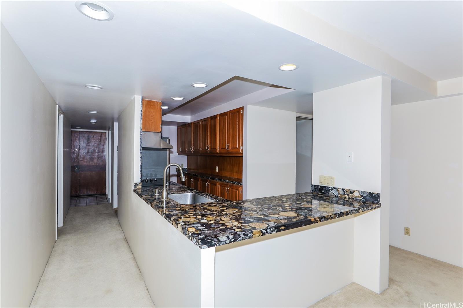 217 Prospect Street, Unit 101 Honolulu, HI 96813 - Photo 8 of 25 a kitchen with kitchen island granite countertop a sink and a refrigerator