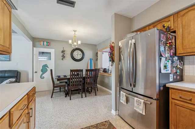 a kitchen with stainless steel appliances granite countertop a refrigerator a stove a dining table and chairs