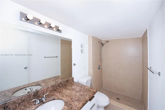 a bathroom with a granite countertop sink a toilet and shower
