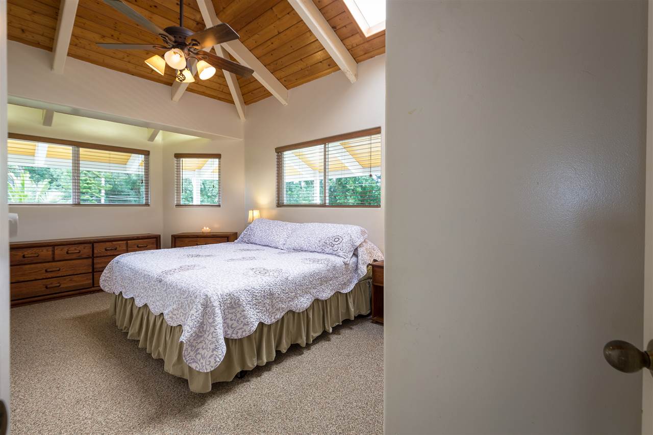 890 East Kuiaha Road Haiku, HI 96708 - Photo 17 of 30 a spacious bedroom with a bed and a chandelier