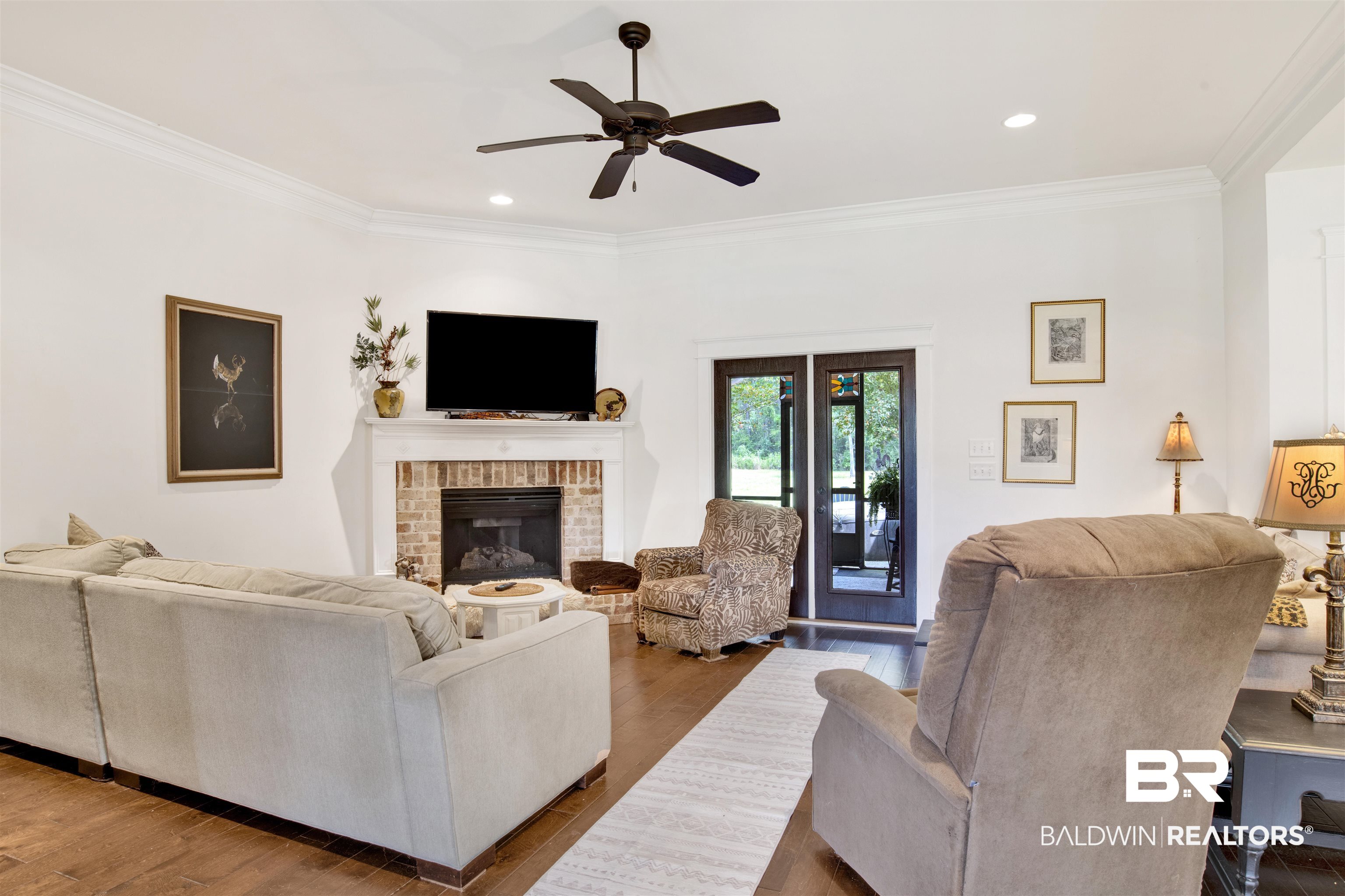 9240 Bay Point Drive Elberta, AL 36530 - Photo 7 of 22 Living room featuring crown molding, ceiling fan, hardwood / wood-style floors, and a brick fireplace