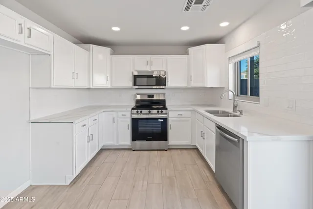 a kitchen with granite countertop a sink cabinets and stainless steel appliances