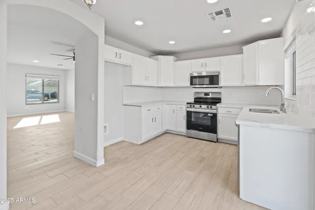 a kitchen with stainless steel appliances granite countertop a stove top oven a sink and a refrigerator