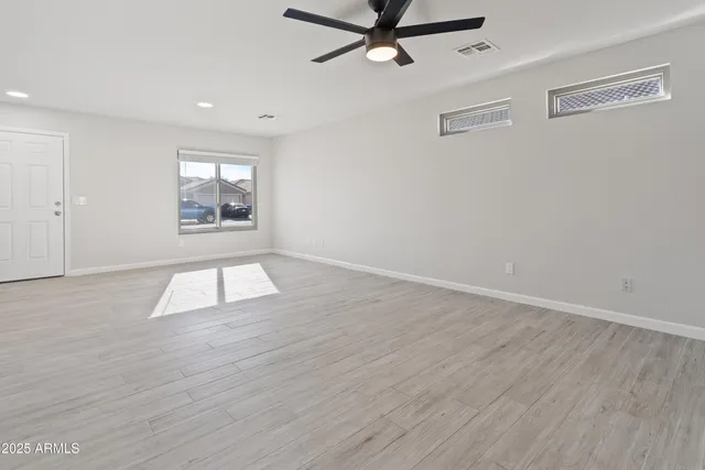 a view of empty room with wooden floor and fan