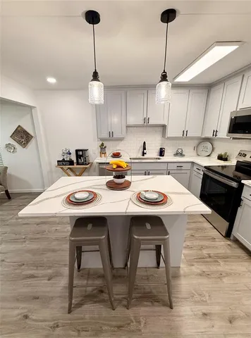 a kitchen with stainless steel appliances kitchen island a table chairs in it and wooden floors