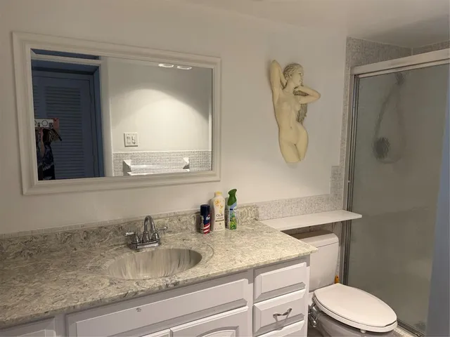 a bathroom with a granite countertop toilet sink and mirror
