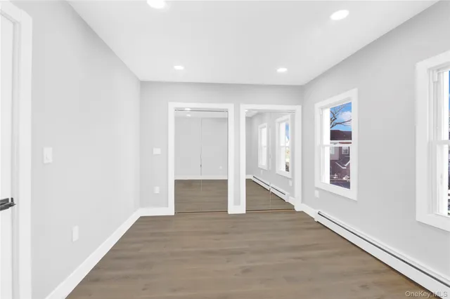 a view of an empty room with wooden floor and windows