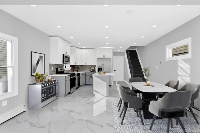 a kitchen with stainless steel appliances kitchen island granite countertop a dining table chairs and a refrigerator