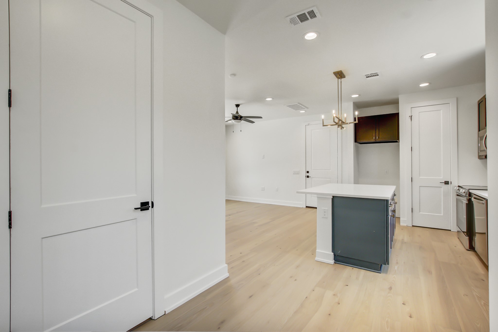 4127 East 12th Street, Unit 8 Austin, TX 78721 - Photo 14 of 32 Kitchen featuring baseboards, a center island, light countertops, a ceiling fan, and light wood-type flooring