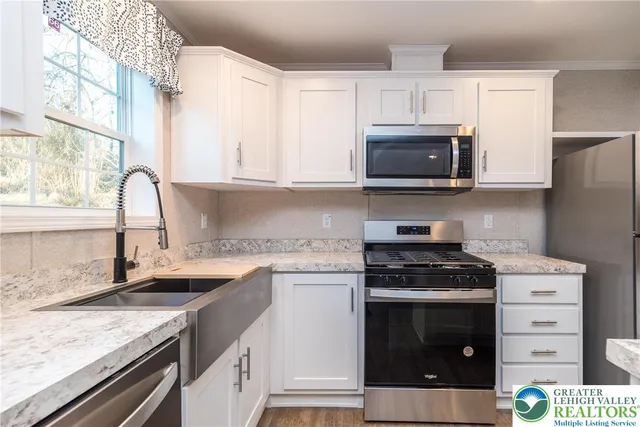a kitchen with granite countertop a stove sink and microwave