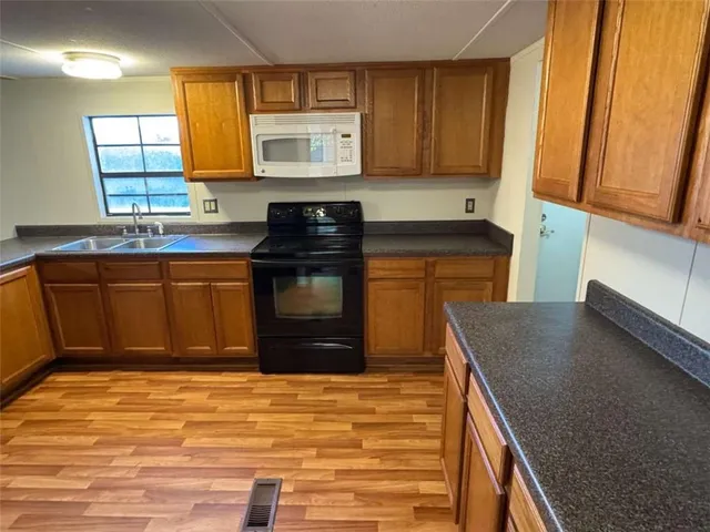 a kitchen with stainless steel appliances granite countertop a stove a sink and a microwave
