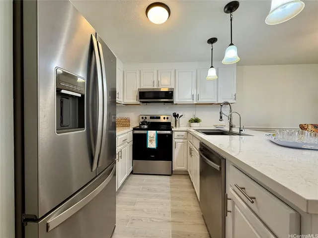 a kitchen with stainless steel appliances granite countertop a refrigerator a sink a stove and white cabinets