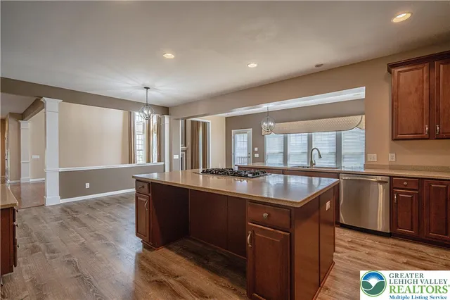 a open kitchen with stainless steel appliances granite countertop a refrigerator a sink dishwasher a stove and a dining table with wooden floor