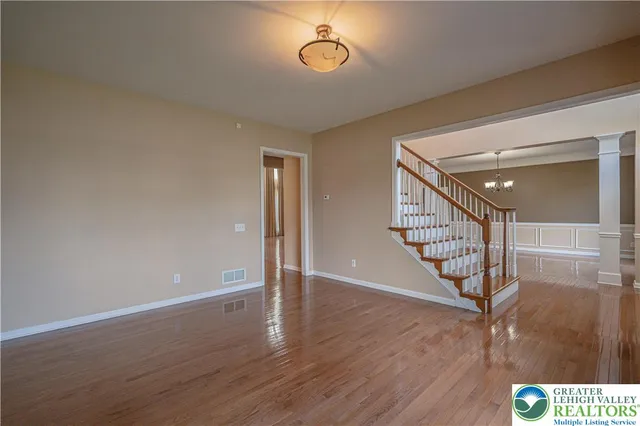 a view of a room with wooden floor chandelier and windows