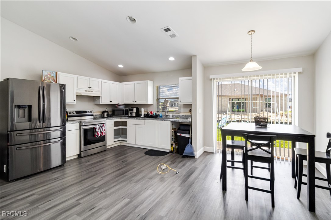 776-778 Alabama Road South Lehigh Acres, FL 33974 - Photo 18 of 50 a kitchen with stainless steel appliances granite countertop a refrigerator a stove top oven a sink dishwasher and white cabinets with wooden floor