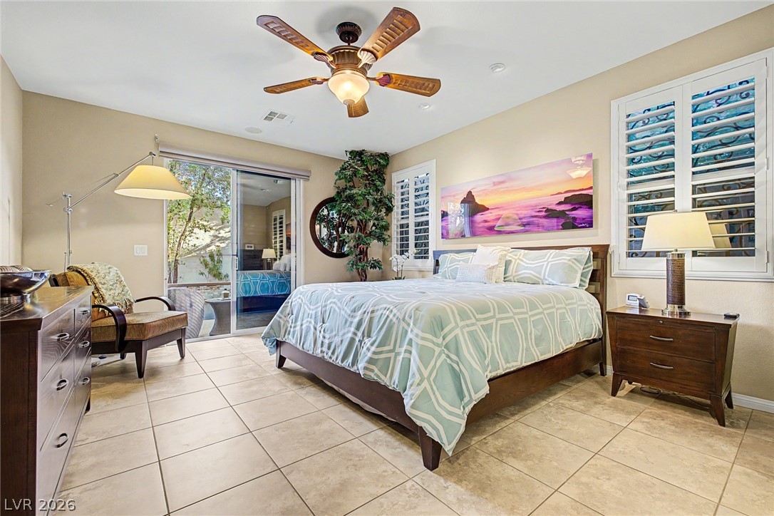 7415 Campbell Ranch Avenue Las Vegas, NV 89179 - Photo 30 of 52 A tranquil bedroom features cool-toned tile flooring and a sliding glass door leading to a private outdoor space.