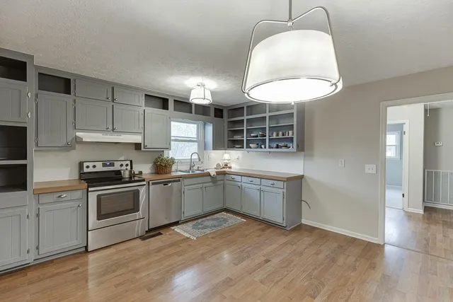a kitchen with stainless steel appliances granite countertop a sink a stove and refrigerator